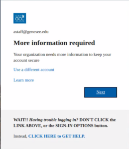 The 'More information required' screen displayed when using the authenticator app for the first time. A GCC logo is displayed, followed by the login ID you are using. The screen reads: "More information required. Your organization needs more information ot keep your accoutn secure. Use a different account. Learn More." The submit button is labeled 'Next.' Below the submit button is help text for GCC users: "WAIT!! Having trouble logging in? DON'T CLICK the LINK ABOVE, or the SIGN IN OPTIONS button. Instead, CLICK HERE to GET HELP.' 